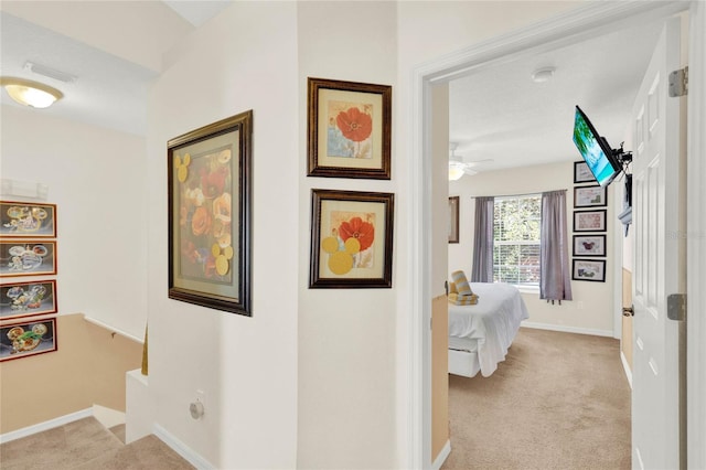 hallway featuring light carpet, visible vents, and baseboards