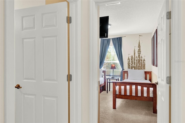 bedroom featuring carpet floors, visible vents, and a textured ceiling