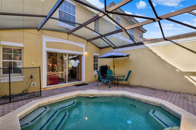 view of pool with glass enclosure, a patio, and a hot tub