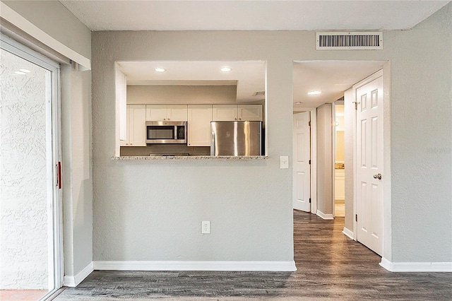 kitchen featuring appliances with stainless steel finishes, dark wood-style flooring, visible vents, and baseboards