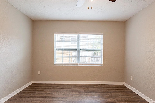 spare room featuring a textured ceiling, a textured wall, dark wood finished floors, and baseboards