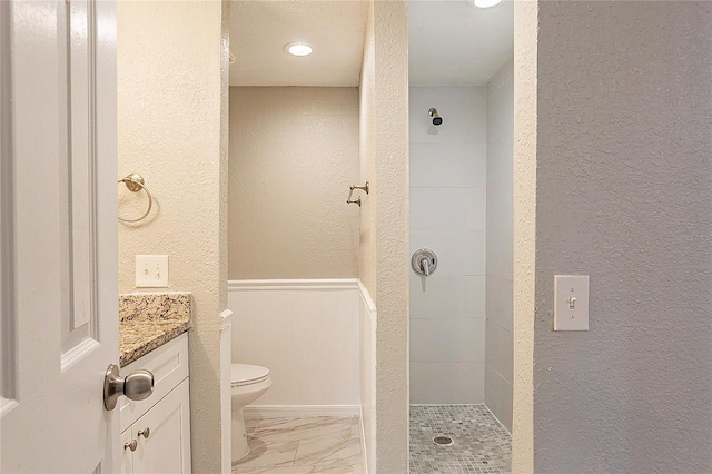 full bathroom with a textured wall, toilet, vanity, marble finish floor, and tiled shower