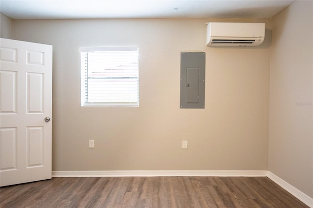 empty room with a wall mounted AC, wood finished floors, electric panel, and baseboards