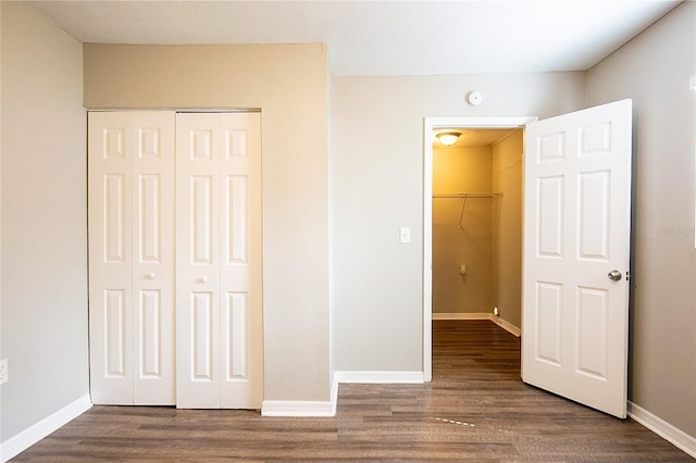 unfurnished bedroom with a closet, baseboards, and wood finished floors