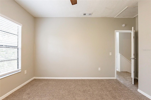 spare room with visible vents, a ceiling fan, light carpet, a textured ceiling, and baseboards