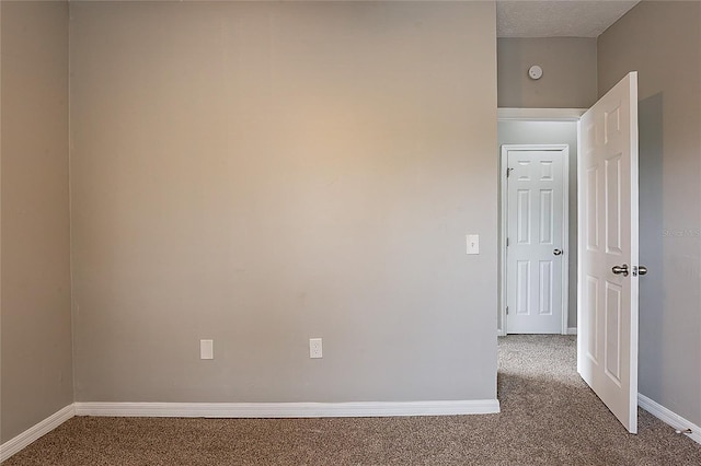 carpeted empty room with a textured ceiling and baseboards