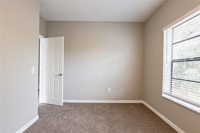 unfurnished room featuring carpet and baseboards