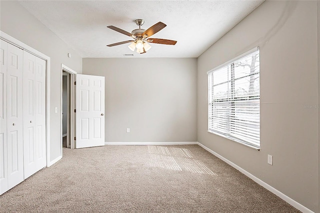 interior space featuring a textured ceiling, ceiling fan, visible vents, baseboards, and carpet