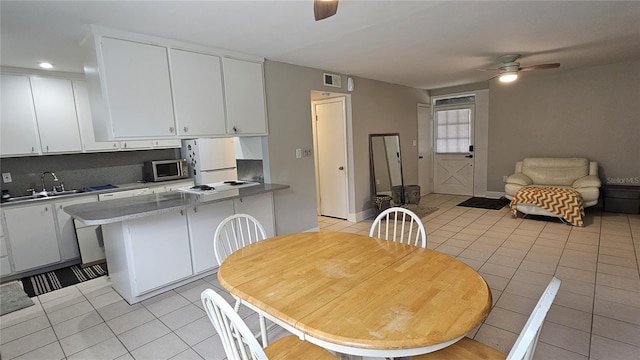 kitchen with ceiling fan, white refrigerator, light tile patterned floors, sink, and white cabinetry