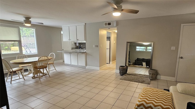 kitchen with sink, white fridge, ceiling fan, light tile patterned floors, and white cabinets