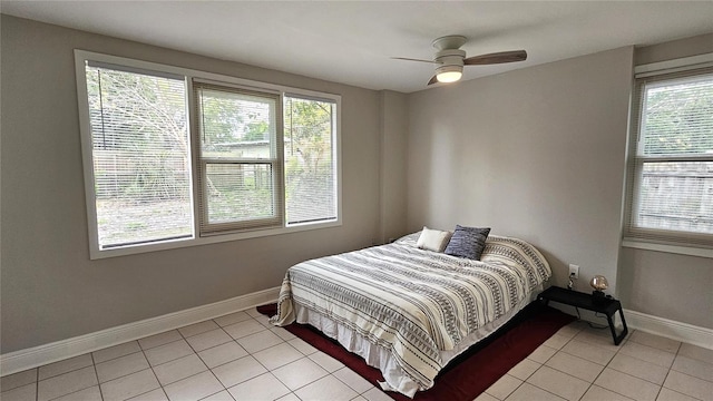 tiled bedroom with ceiling fan and multiple windows