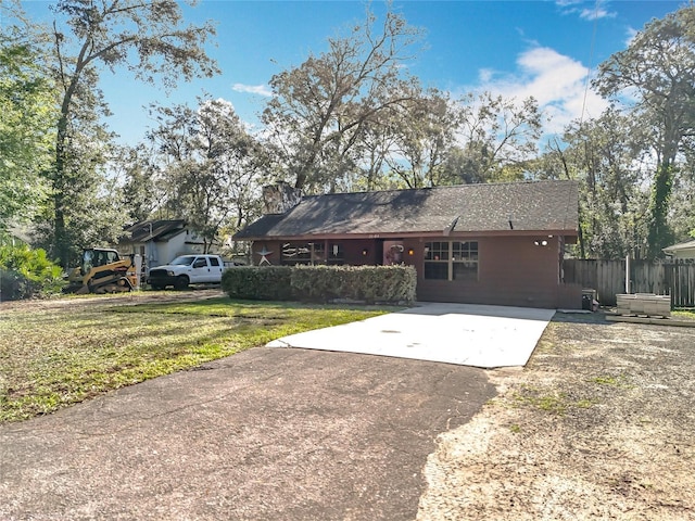 view of front of house with driveway, fence, and a front yard