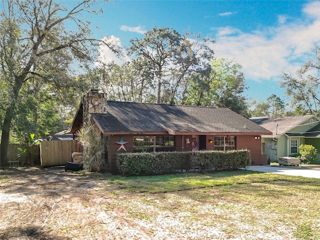 ranch-style home with a chimney, a front yard, and fence