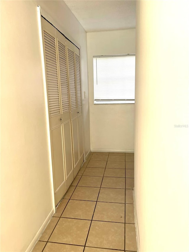 hall featuring baseboards and light tile patterned floors