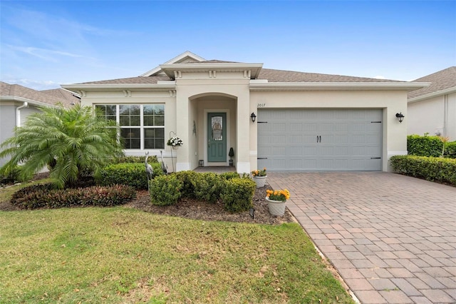 view of front facade with a front lawn, decorative driveway, an attached garage, and stucco siding