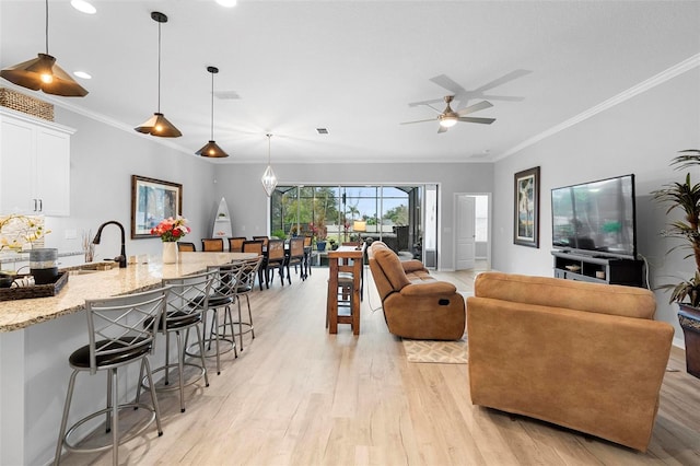 living room with light wood-type flooring, ceiling fan, visible vents, and ornamental molding