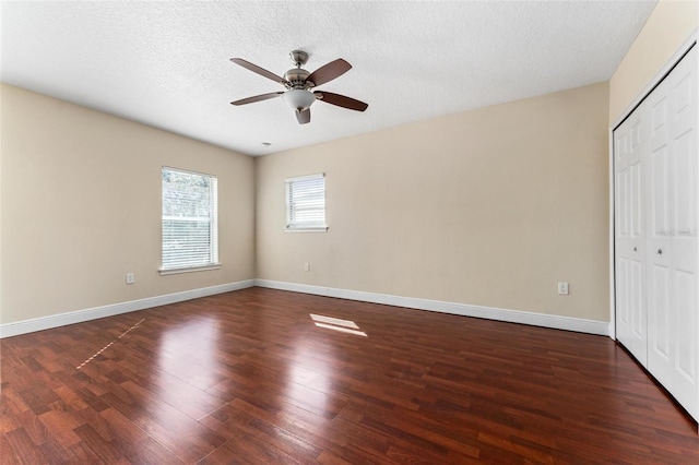 unfurnished bedroom with a textured ceiling, dark wood-type flooring, a closet, and baseboards