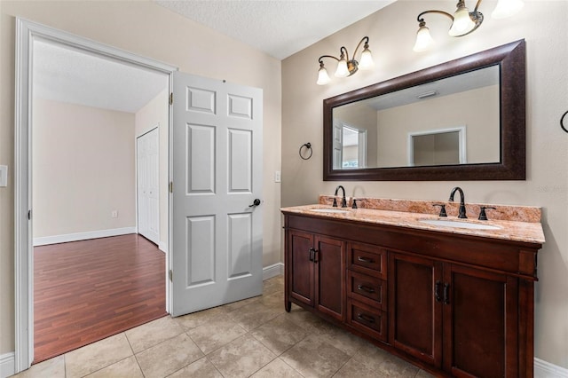 full bath featuring double vanity, a textured ceiling, a sink, and tile patterned floors