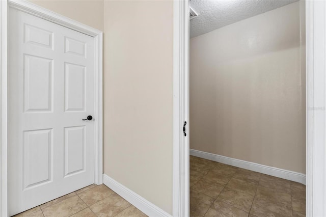 bathroom with a textured ceiling, baseboards, and tile patterned floors