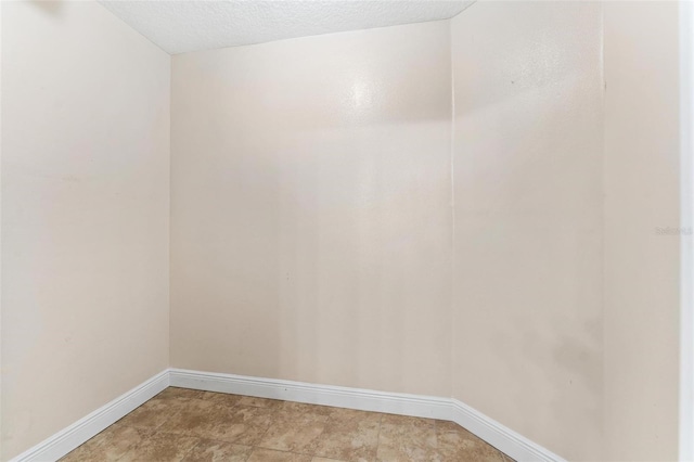 spare room with a textured ceiling and baseboards