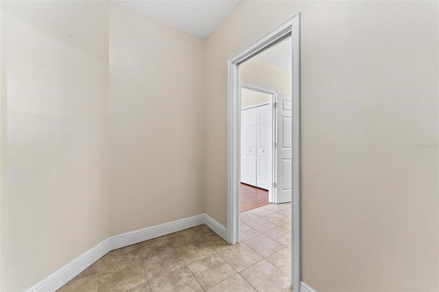 hallway featuring light tile patterned flooring and baseboards