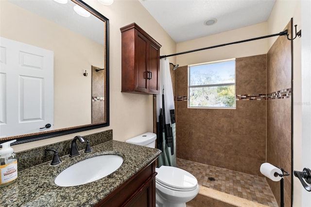 full bathroom featuring toilet, a tile shower, and vanity