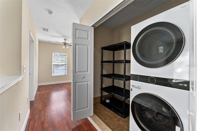 washroom featuring laundry area, visible vents, dark wood-type flooring, a textured ceiling, and stacked washing maching and dryer