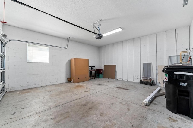 garage featuring concrete block wall and a garage door opener