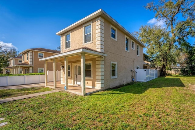 rear view of house with a lawn, a patio area, fence, and stucco siding