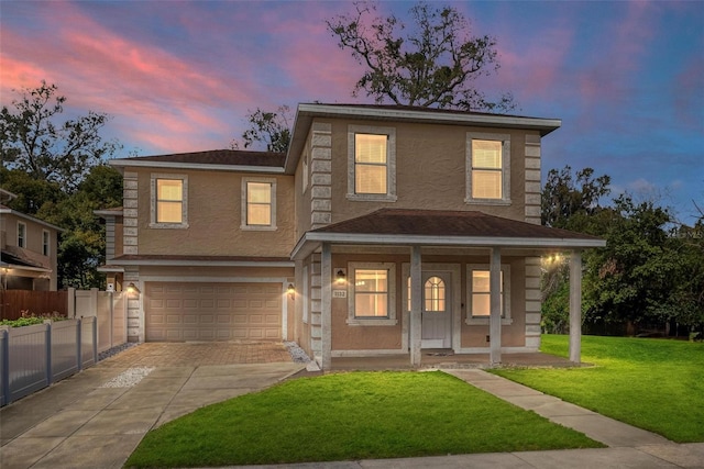 traditional home featuring a yard, stucco siding, a porch, concrete driveway, and fence