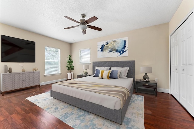 bedroom featuring a textured ceiling, a closet, wood finished floors, and baseboards