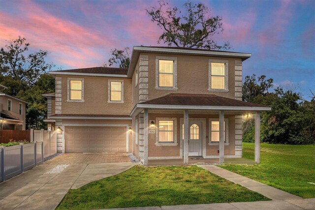 traditional-style home with an attached garage, fence, concrete driveway, stucco siding, and a front yard