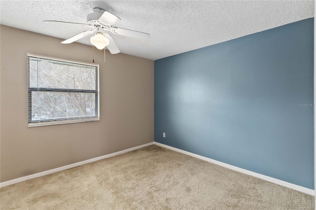 spare room featuring light colored carpet, a textured ceiling, and baseboards