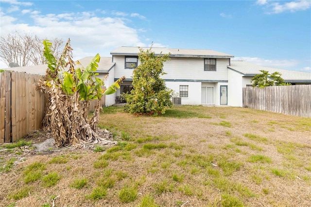 rear view of property featuring a fenced backyard, central AC, and a yard