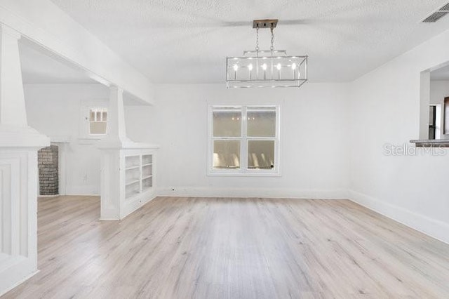 unfurnished dining area with wood finished floors, baseboards, and a textured ceiling