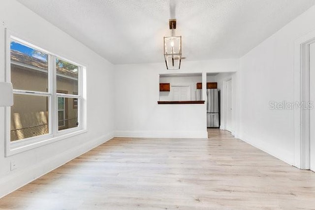 spare room featuring wood finished floors, baseboards, and a textured ceiling