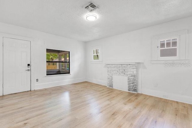 spare room featuring a textured ceiling, wood finished floors, baseboards, and a fireplace