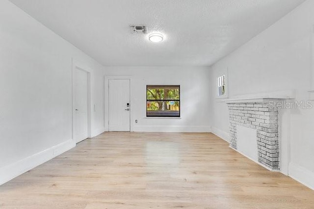 unfurnished room featuring light wood-style floors, baseboards, and a textured ceiling