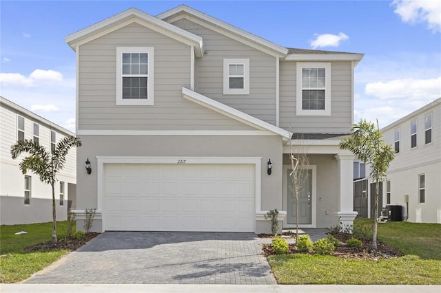 view of front of house with a garage, central AC, and a front lawn