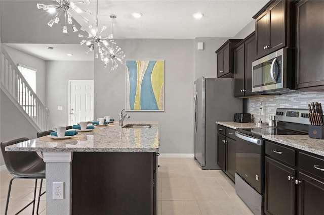 kitchen with a center island with sink, sink, tasteful backsplash, appliances with stainless steel finishes, and a breakfast bar area