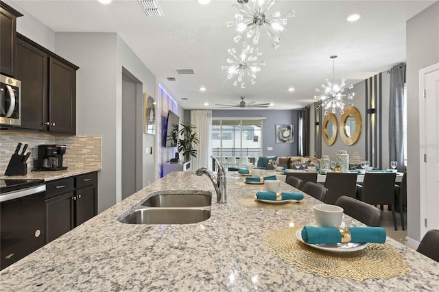 kitchen featuring range, dark brown cabinets, light stone counters, decorative backsplash, and sink