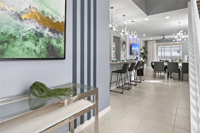 tiled dining room featuring ceiling fan with notable chandelier