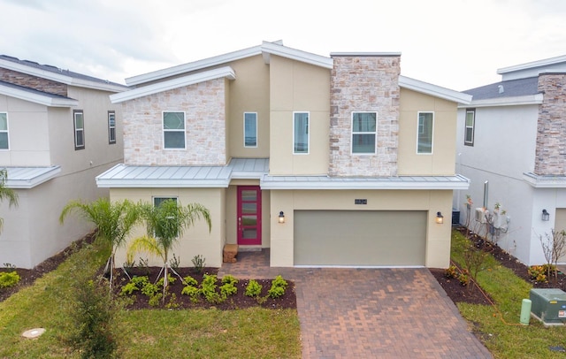 view of front of house featuring a standing seam roof, metal roof, decorative driveway, and stucco siding