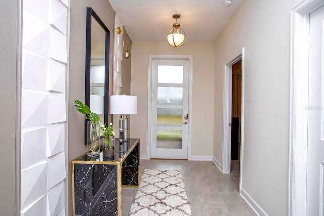 doorway to outside with light tile patterned flooring and baseboards