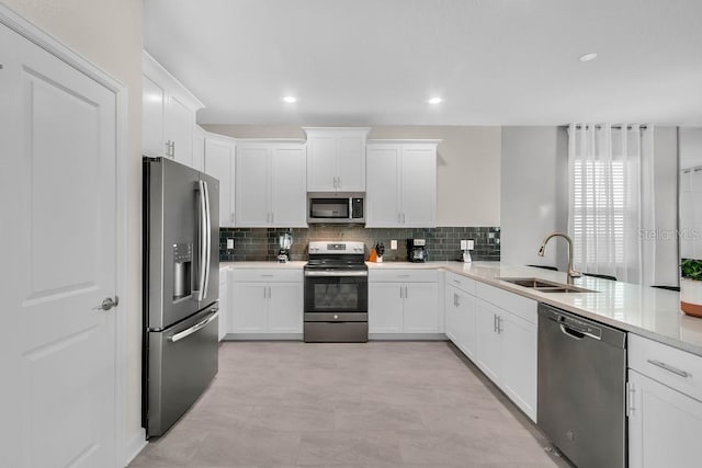 kitchen featuring appliances with stainless steel finishes, a sink, white cabinetry, and decorative backsplash