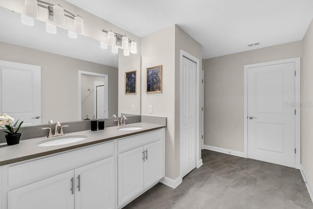 bathroom featuring a closet, visible vents, a sink, and double vanity