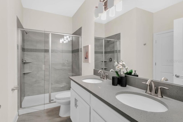 full bathroom featuring a stall shower, a sink, toilet, and double vanity