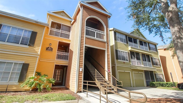 view of property with a garage, concrete driveway, and stairs