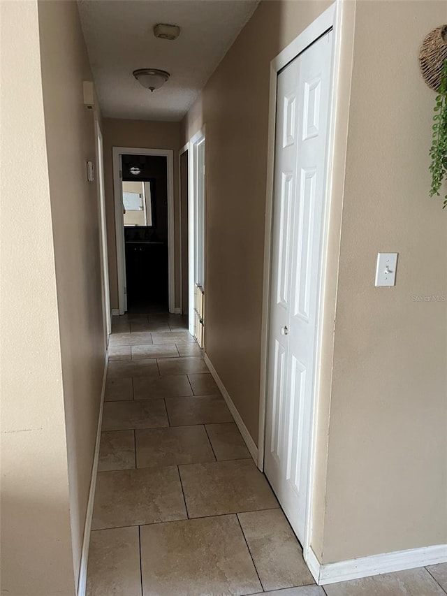 corridor with light tile patterned floors and baseboards