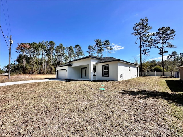 view of front of property featuring a garage, concrete driveway, fence, and stucco siding